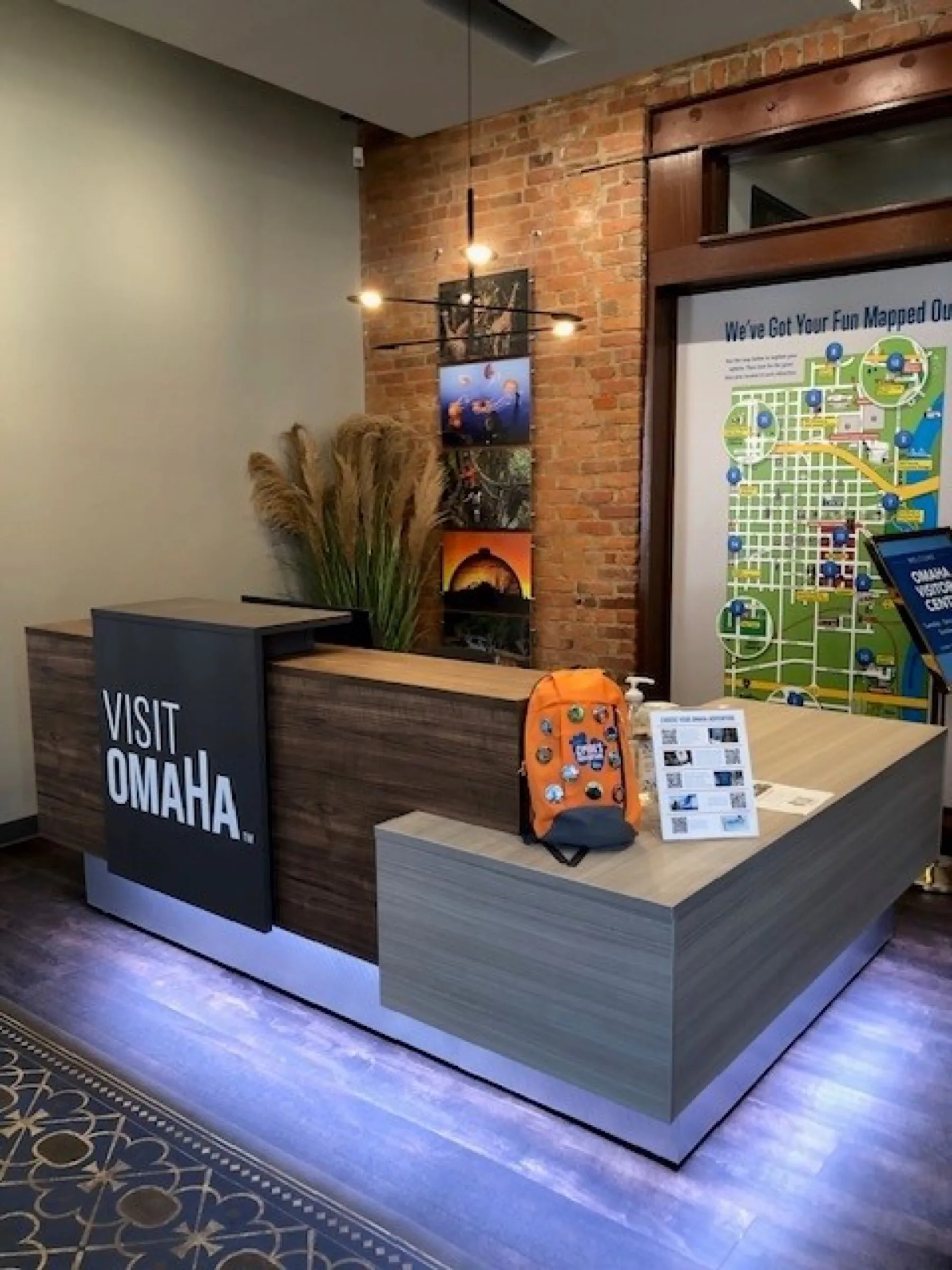 Visitor centre reception desk with backlit signage and exposed brick